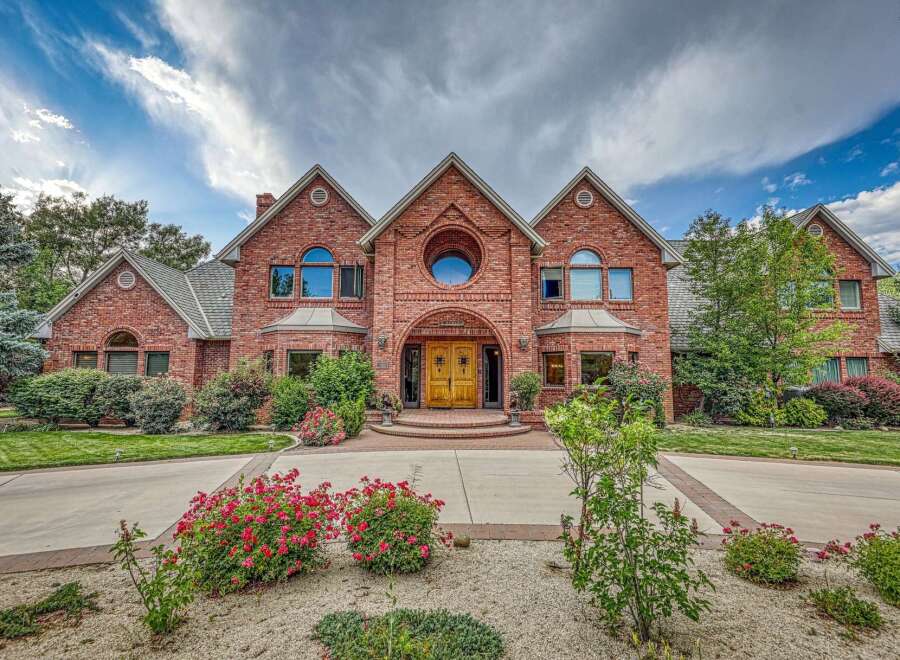 Discover this stunning brick estate featuring a grand entrance with double wooden doors and a unique circular window above.