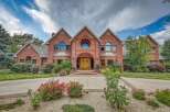 Discover this stunning brick estate featuring a grand entrance with double wooden doors and a unique circular window above.