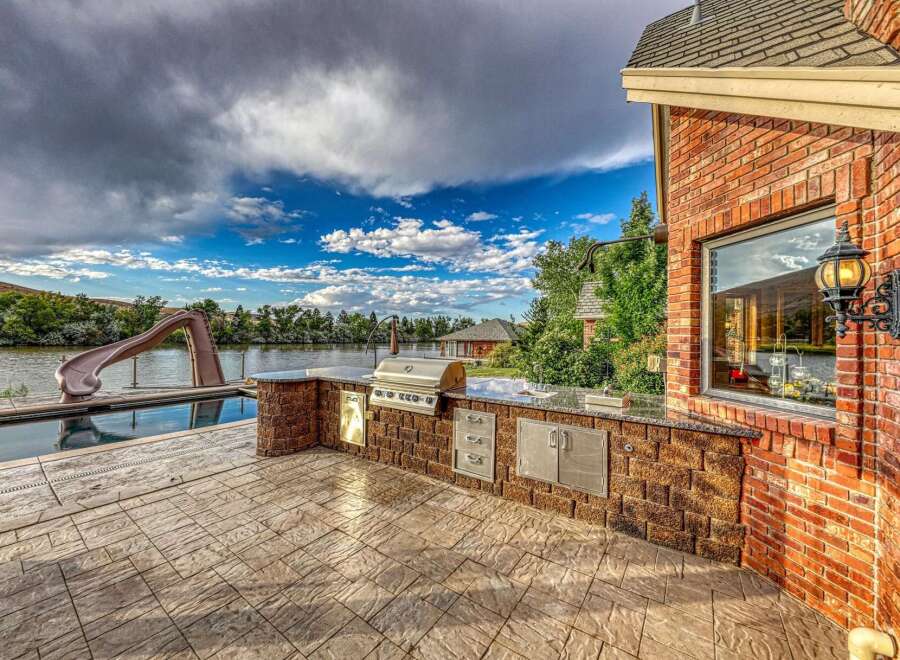 Experience luxury outdoor living with this stunning backyard oasis, featuring a sparkling pool with a water slide and a fully equipped outdoor kitchen.