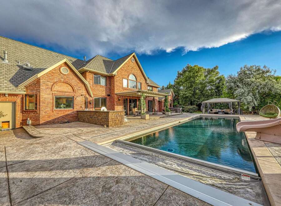 Experience luxurious outdoor living with this stunning brick home featuring a large swimming pool and expansive stamped concrete patio.