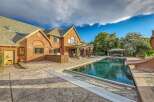 Experience luxurious outdoor living with this stunning brick home featuring a large swimming pool and expansive stamped concrete patio.