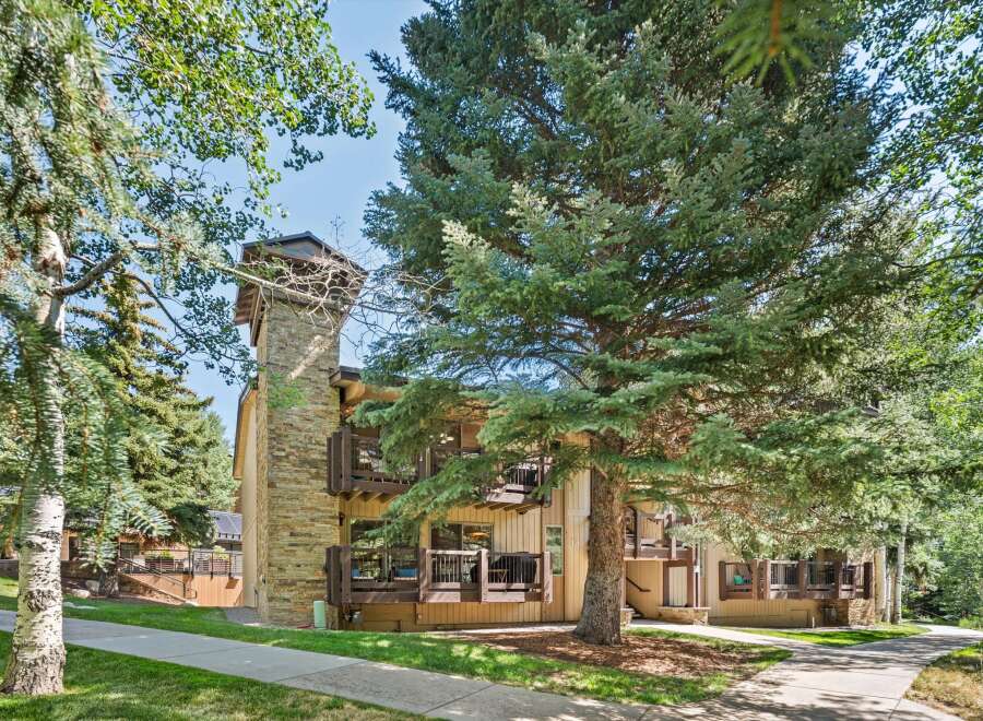 Nestled amidst lush greenery, this charming property features a striking stone chimney and multiple balconies offering serene views.