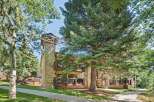 Nestled amidst lush greenery, this charming property features a striking stone chimney and multiple balconies offering serene views.