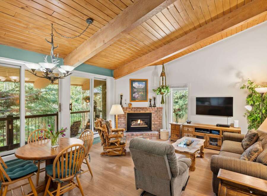Experience rustic charm in this inviting living space featuring a vaulted wood-beamed ceiling and a cozy brick fireplace.