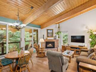 Experience rustic charm in this inviting living space featuring a vaulted wood-beamed ceiling and a cozy brick fireplace.