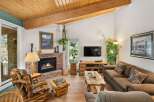 Cozy up by the brick fireplace in this inviting living room, featuring rustic log furniture and a beautiful wooden ceiling.