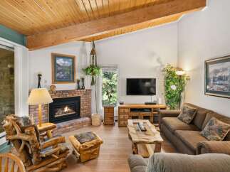 Cozy up by the brick fireplace in this inviting living room, featuring rustic log furniture and a beautiful wooden ceiling.