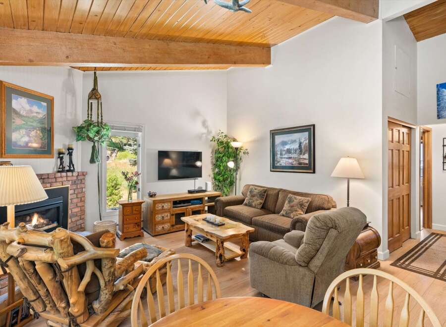 Cozy living room featuring a rustic stone fireplace, a comfortable sofa, and a unique log-style armchair.