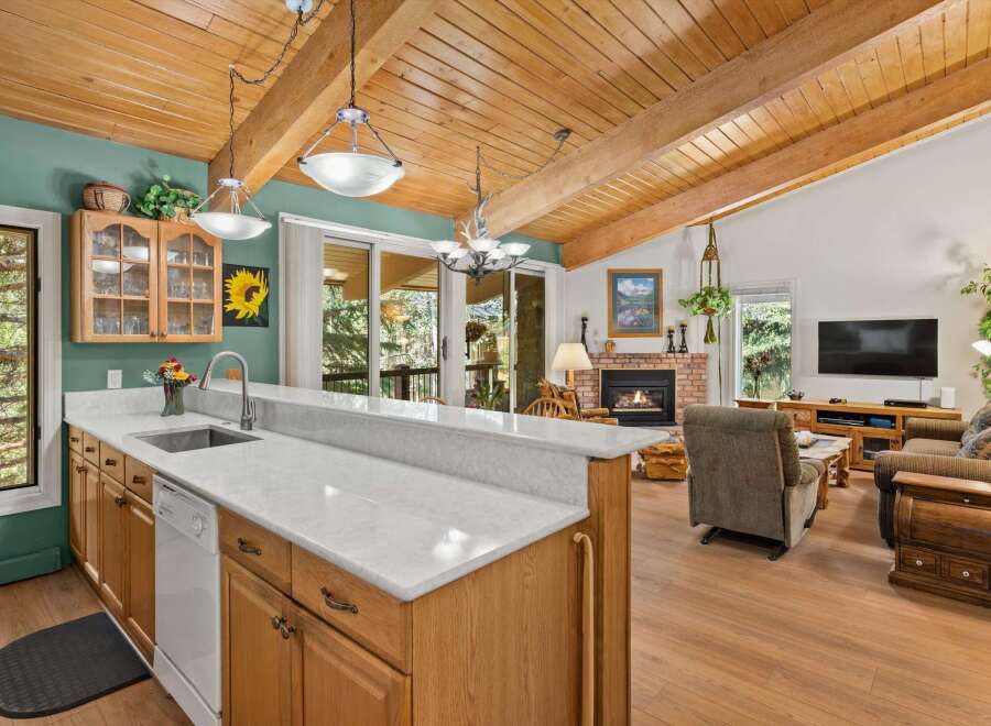 Experience rustic charm in this open-concept living space, featuring a vaulted wood-beamed ceiling and a cozy brick fireplace.