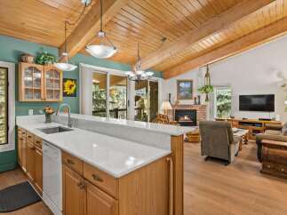 Experience rustic charm in this open-concept living space, featuring a vaulted wood-beamed ceiling and a cozy brick fireplace.