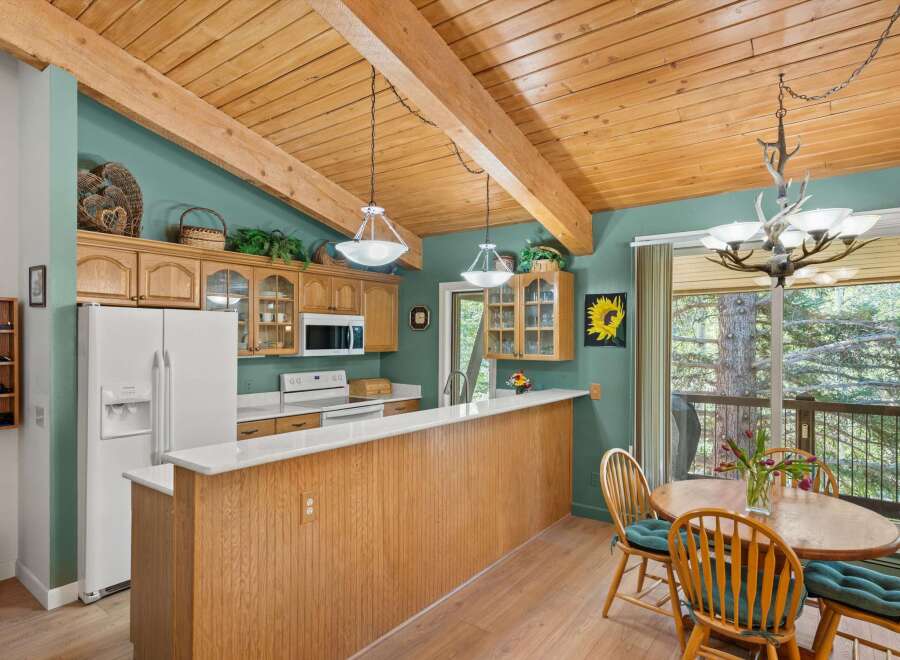 This charming kitchen boasts a vaulted wood-beamed ceiling and ample natural light, creating a warm and inviting atmosphere.