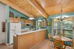 This charming kitchen boasts a vaulted wood-beamed ceiling and ample natural light, creating a warm and inviting atmosphere.