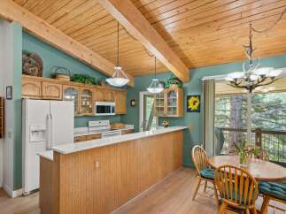 This charming kitchen boasts a vaulted wood-beamed ceiling and ample natural light, creating a warm and inviting atmosphere.