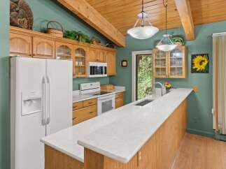 Discover this charming kitchen featuring warm wooden cabinetry and a spacious quartz countertop island, perfect for meal preparation and casual dining.