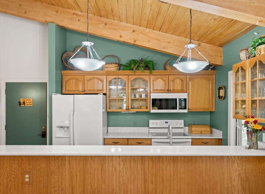 This charming kitchen features warm wooden cabinetry and a vaulted ceiling with exposed beams, creating a cozy and inviting atmosphere.