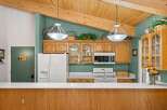 This charming kitchen features warm wooden cabinetry and a vaulted ceiling with exposed beams, creating a cozy and inviting atmosphere.