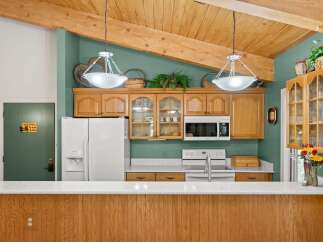 This charming kitchen features warm wooden cabinetry and a vaulted ceiling with exposed beams, creating a cozy and inviting atmosphere.