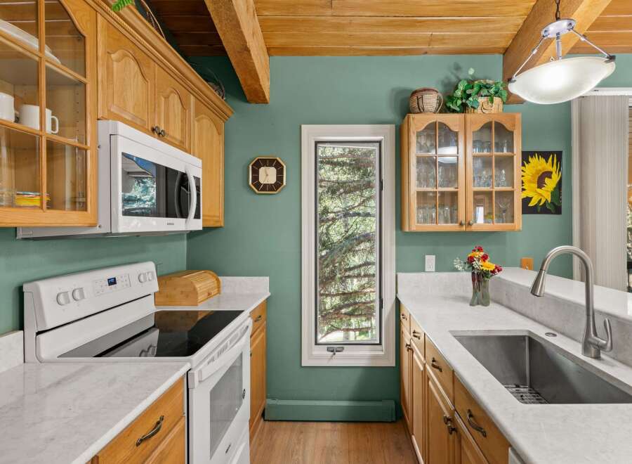 Discover this charming kitchen featuring warm oak cabinetry and elegant marble countertops.