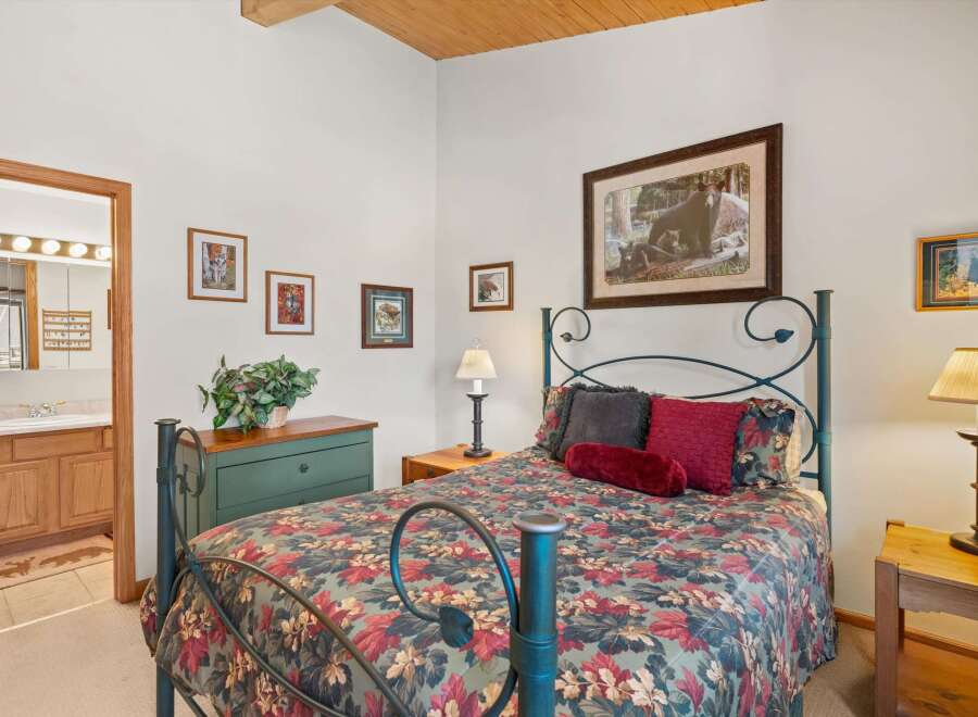 Experience rustic charm in this cozy bedroom featuring a queen-size bed with a floral comforter and a dark metal frame.