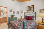 Experience rustic charm in this cozy bedroom featuring a queen-size bed with a floral comforter and a dark metal frame.