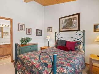Experience rustic charm in this cozy bedroom featuring a queen-size bed with a floral comforter and a dark metal frame.