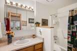 This charming bathroom features a spacious vanity with a marble-look countertop and a large mirror with overhead lighting.