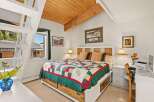 Experience cozy comfort in this charming bedroom featuring a rustic wooden headboard and a vibrant, nature-themed quilt.