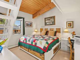 Experience cozy comfort in this charming bedroom featuring a rustic wooden headboard and a vibrant, nature-themed quilt.