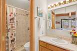 This charming bathroom features a shower with a unique moose and maple leaf shower curtain, complementing the tiled walls and floor.