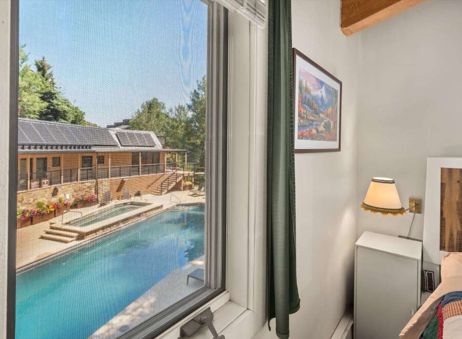 Enjoy a refreshing dip in the sparkling pool, surrounded by lush greenery and a charming building with solar panels.