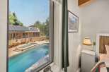 Enjoy a refreshing dip in the sparkling pool, surrounded by lush greenery and a charming building with solar panels.