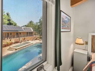 Enjoy a refreshing dip in the sparkling pool, surrounded by lush greenery and a charming building with solar panels.