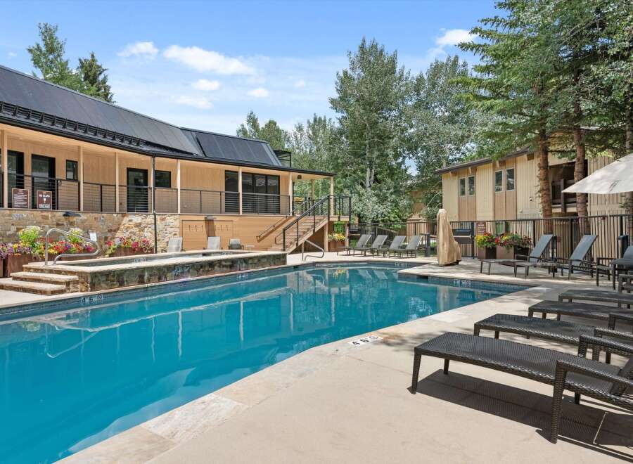 Enjoy a refreshing dip in the sparkling blue pool, surrounded by lush landscaping and comfortable lounge chairs.