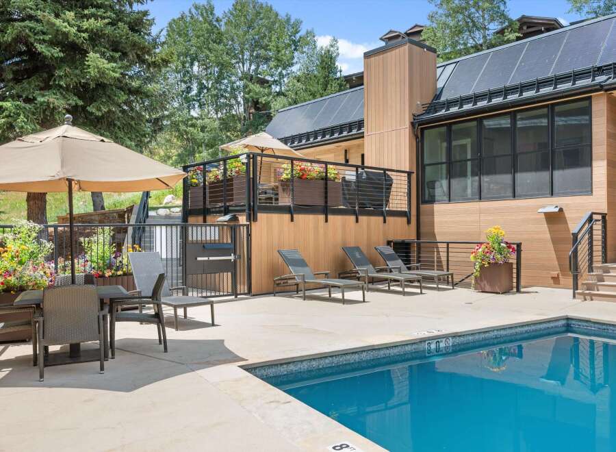 Enjoy a refreshing dip in the sparkling blue pool, surrounded by a modern patio and lush greenery.