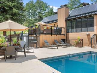 Enjoy a refreshing dip in the sparkling blue pool, surrounded by a modern patio and lush greenery.