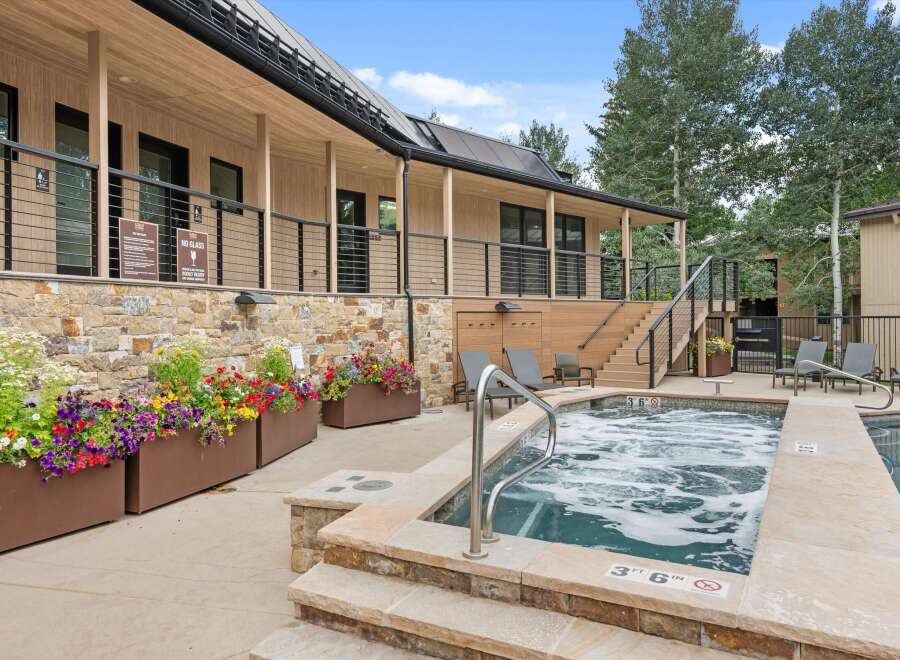 Enjoy a relaxing soak in the bubbling hot tub, surrounded by vibrant flowers and modern architecture.