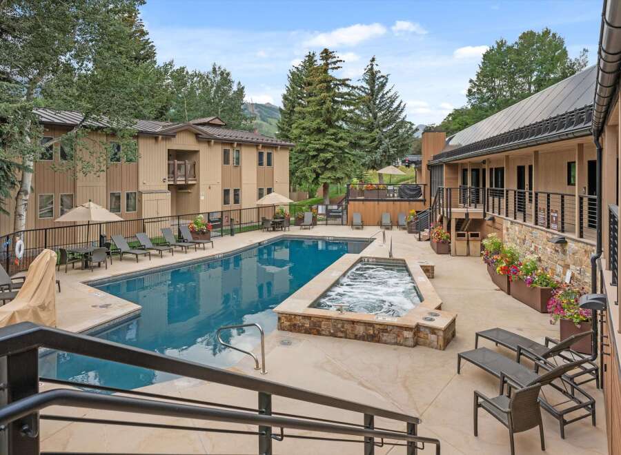 Enjoy a refreshing dip in the sparkling blue swimming pool or relax in the bubbling hot tub, surrounded by lush trees and mountain views.