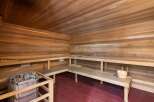 Experience ultimate relaxation in this luxurious wooden sauna, featuring ample seating and a modern heater with stones.