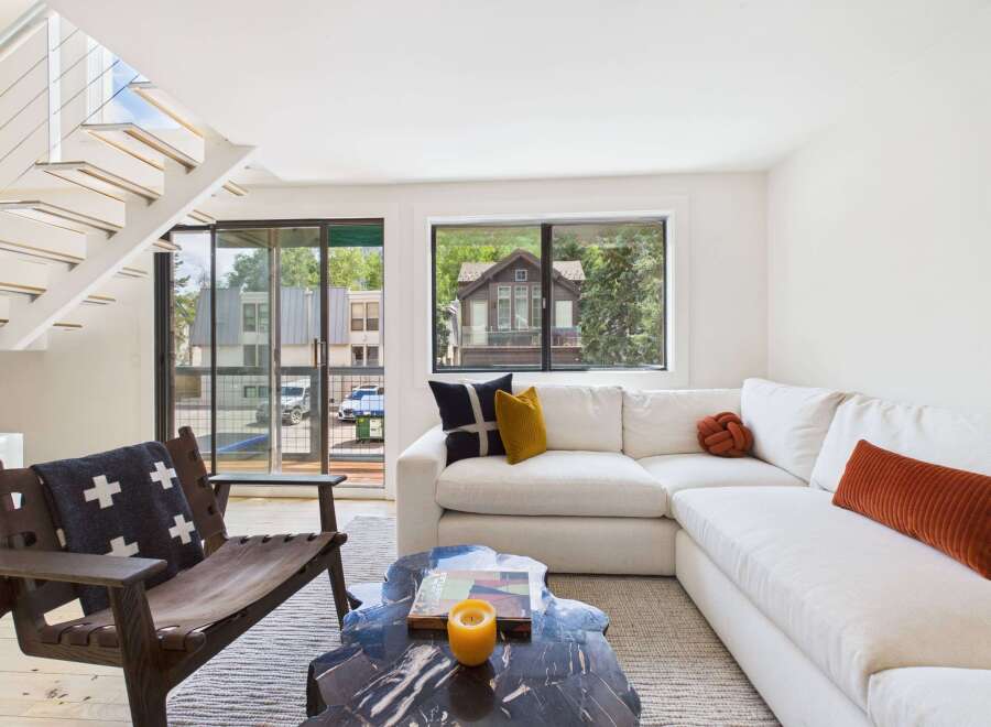 Experience modern living in this bright and airy space, featuring a sleek white sectional sofa complemented by accent pillows and a unique knot pillow.