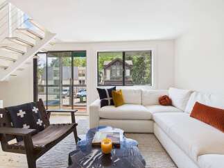 Experience modern living in this bright and airy space, featuring a sleek white sectional sofa complemented by accent pillows and a unique knot pillow.