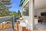Enjoy your morning coffee on this charming balcony, complete with two white chairs and a small table, offering a perfect spot to relax amidst the lush greenery.