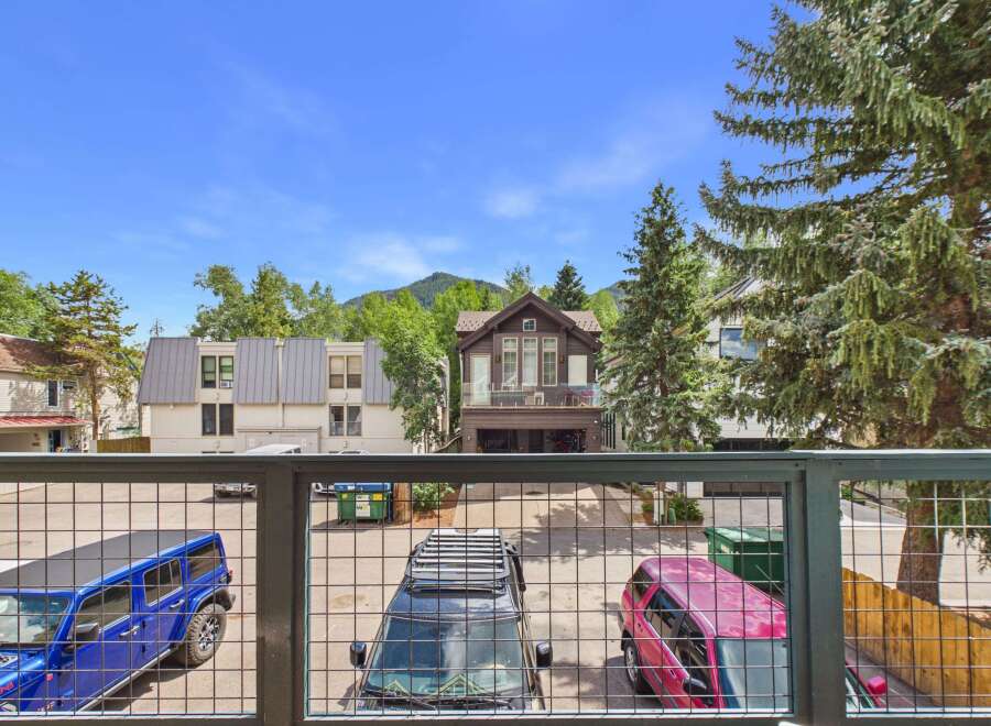 Experience mountain living with this stunning property featuring a spacious balcony overlooking a private parking area with multiple vehicles.