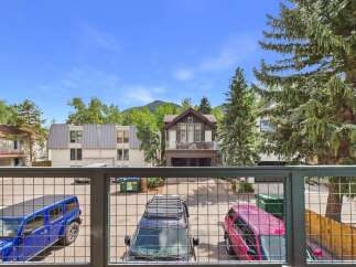 Experience mountain living with this stunning property featuring a spacious balcony overlooking a private parking area with multiple vehicles.