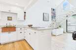 Experience modern living in this bright and airy kitchen featuring crisp white cabinetry, a stunning copper farmhouse sink, and a sleek granite countertop island with a built-in stovetop.