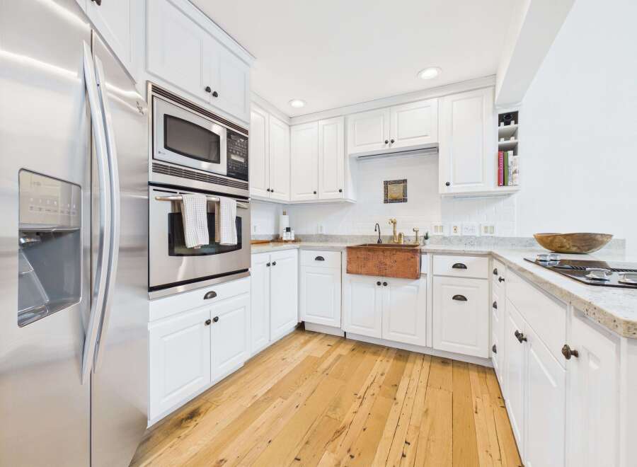 This bright and airy kitchen features sleek stainless steel appliances, including a built-in microwave and oven, complemented by crisp white cabinetry.