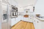 This bright and airy kitchen features sleek stainless steel appliances, including a built-in microwave and oven, complemented by crisp white cabinetry.