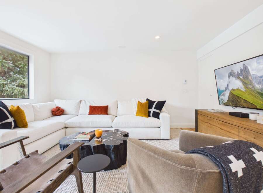 Experience modern living in this stylish living room, featuring a spacious sectional sofa adorned with decorative pillows and a unique, natural wood coffee table.