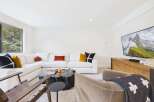 Experience modern living in this stylish living room, featuring a spacious sectional sofa adorned with decorative pillows and a unique, natural wood coffee table.