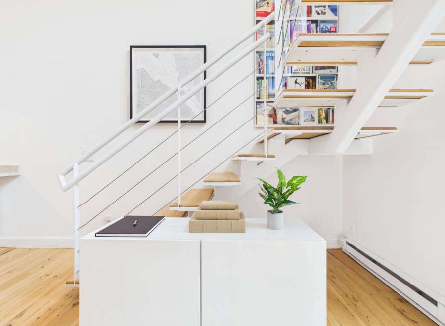 This modern staircase features a unique open-riser design with integrated shelving, perfect for displaying books and decor.