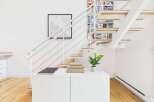 This modern staircase features a unique open-riser design with integrated shelving, perfect for displaying books and decor.